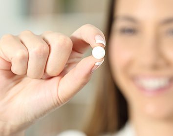 Patient smiling while holding an oral conscious sedation pill in Morgan Hill