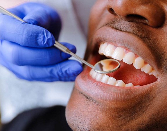 dentist using small mirror to examine patient