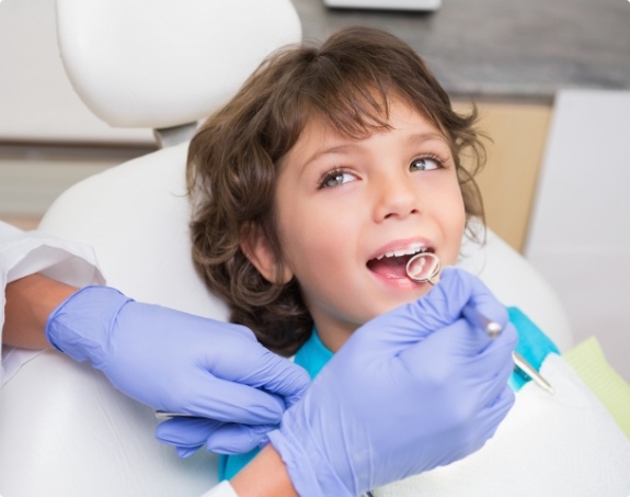 Child receiving dental checkup and teeth cleaning from children's dentist