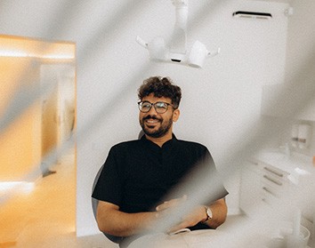 Patient with black glasses smiling in treatment chair