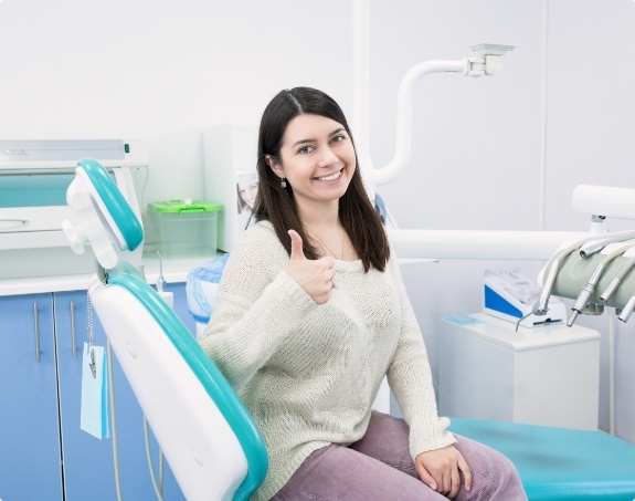 Woman in dental chair giving a thumbs up