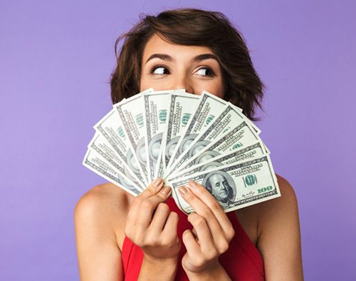 Woman hiding her smile behind a fan of money