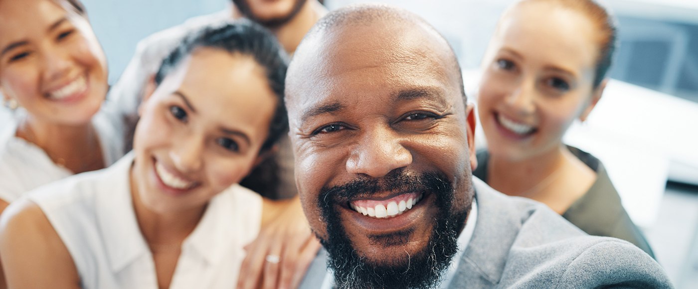 a group of coworkers smiling and taking a selfie together