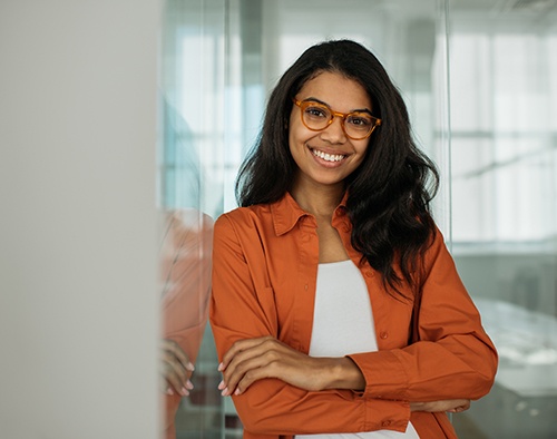 a smiling business woman leaning against a wall