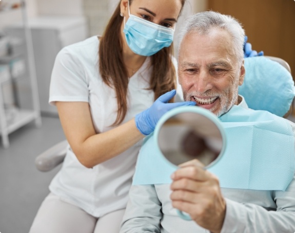 Man looking at smile and enjoying the benefits of dental implants