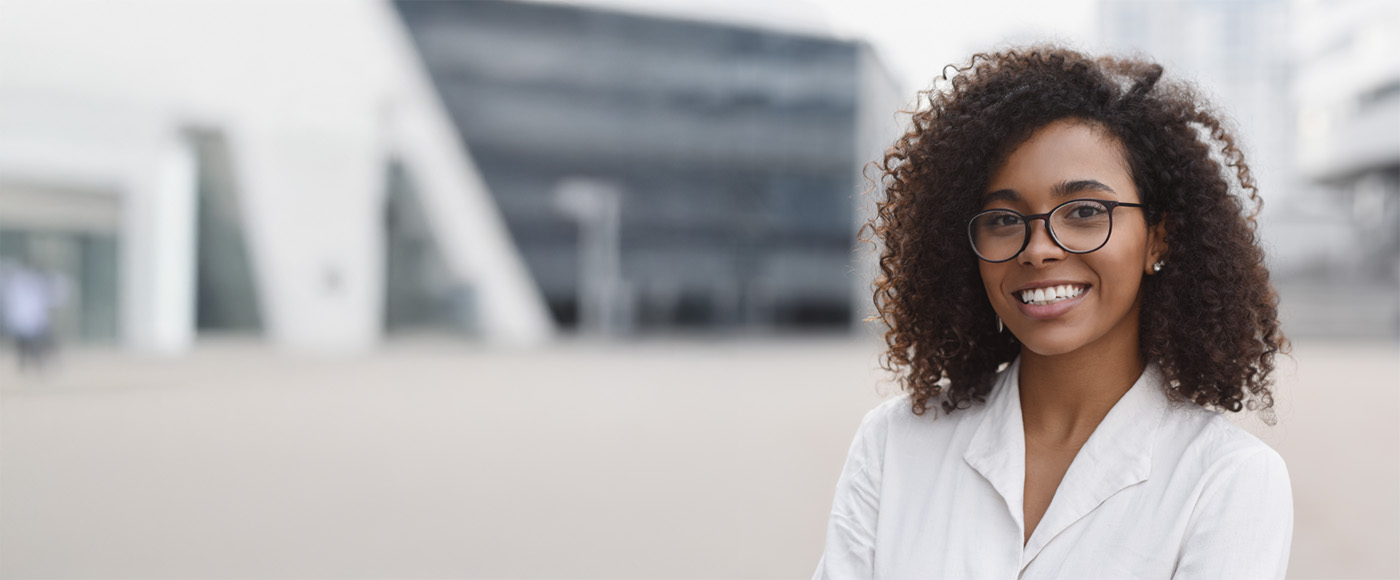 A cheerful woman wearing glasses and a white shirt, symbolizing a welcoming dentist ready to assist patients.