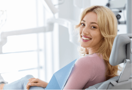 A woman sitting in a dental chair, smiling confidently, showcasing a positive dental experience.