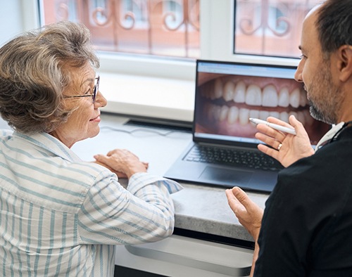 Dentist and patient looking at photo of her smile on computer screen
