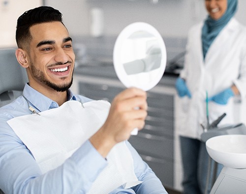 Man smiling at reflection in mirror in treatment chair