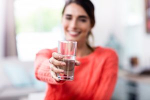 a woman smiling and holding a glass of water