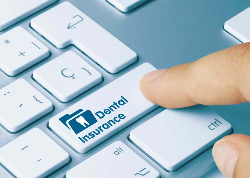 A finger pressing a keyboard button labelled “dental insurance”