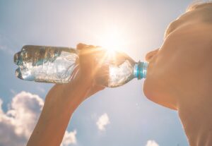Sun beaming down on person drinking water.